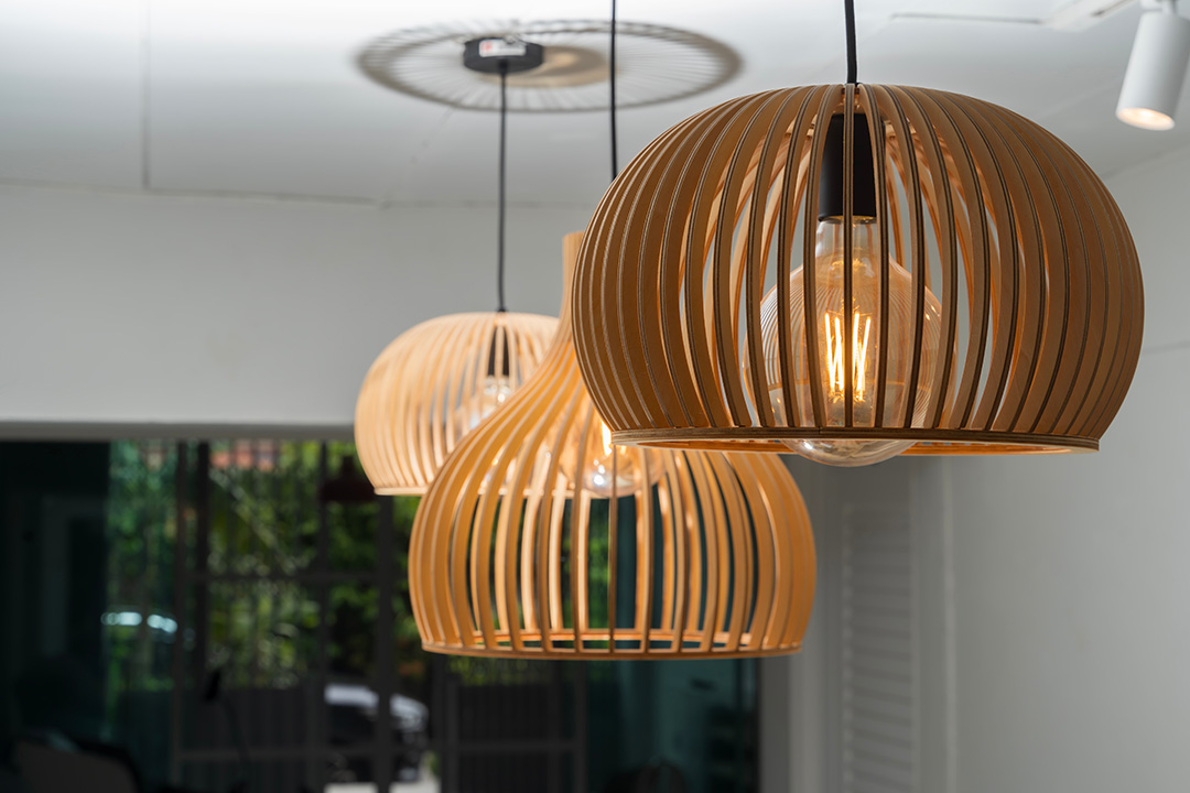 Modern pendant lamps made of wooden slats hanging from the ceiling, glowing with warm light. Interior decor idea for cozy and stylish home or cafe ambiance. Contemporary and minimalist lighting design